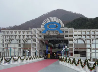 Entrance building of NEW Reoma World theme park with its round logo, hills behind