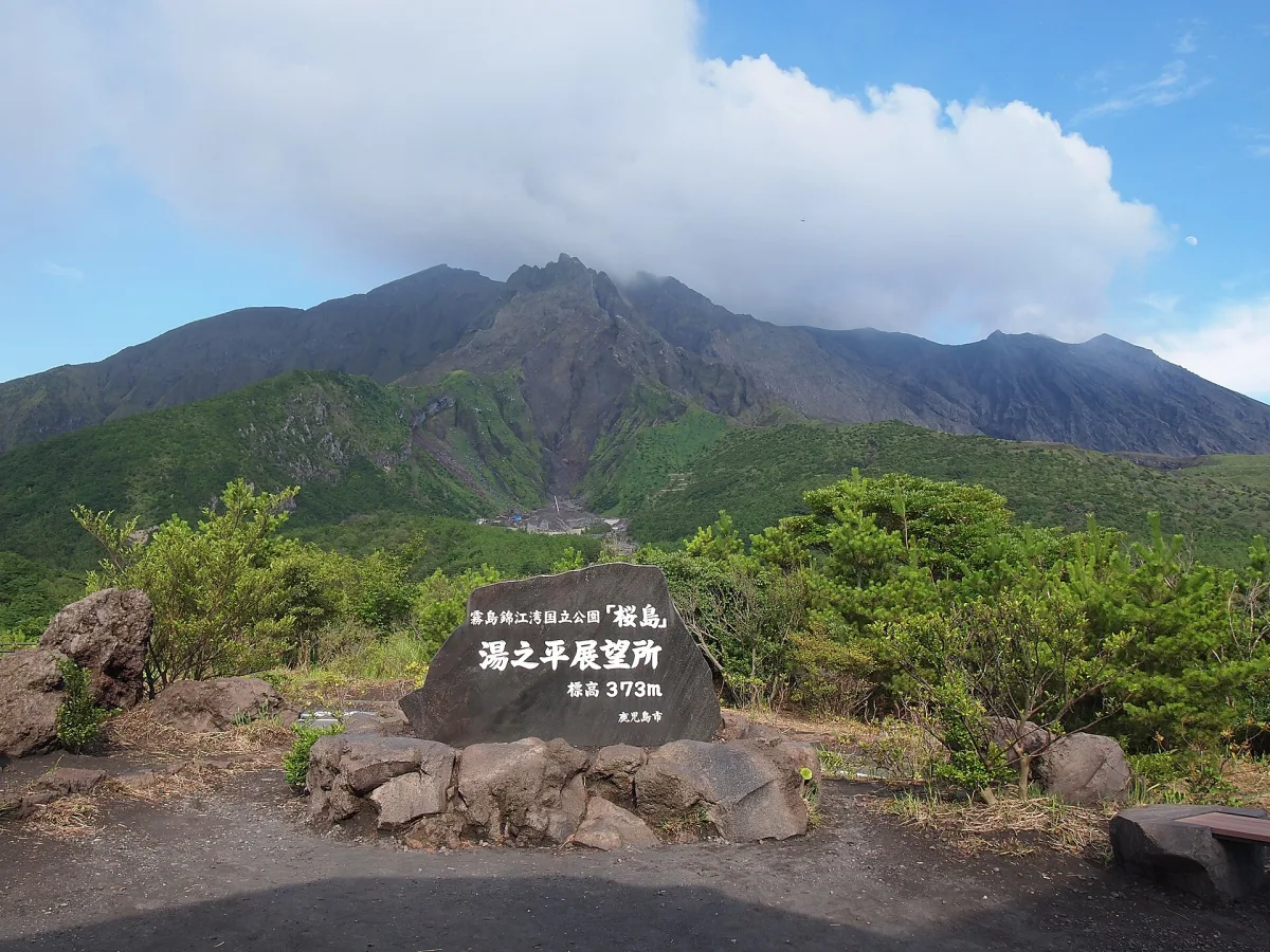 The Yunohira Observatory stone marker with the rugged peaks of Sakurajima behind