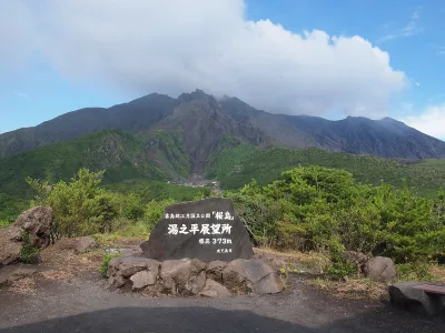 The Yunohira Observatory stone marker with the rugged peaks of Sakurajima behind