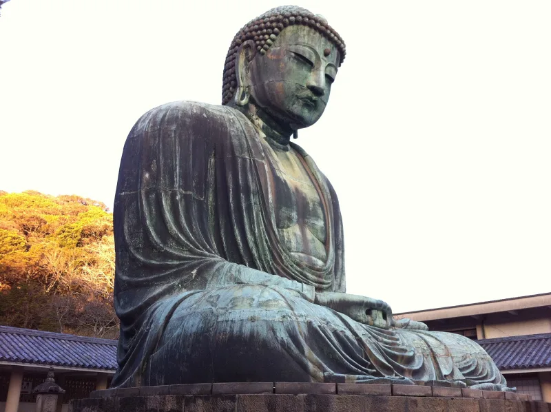 The Great Buddha of Kamakura seen at an angle, showing its robes and hands