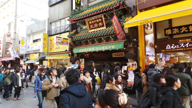 Crowds walking along a busy street of shops and restaurants in Yokohama Chinatown