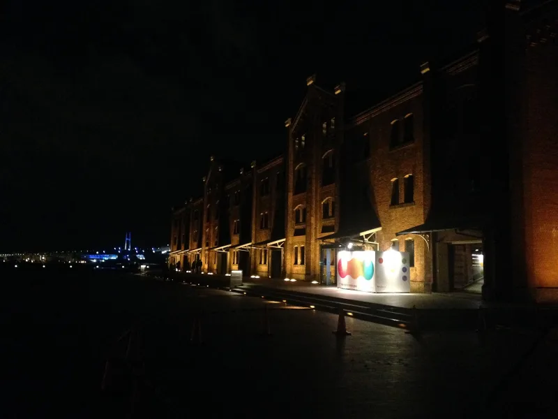 Red Brick Warehouse Building No. 1 lit up at night with Yokohama Bay Bridge in the distance