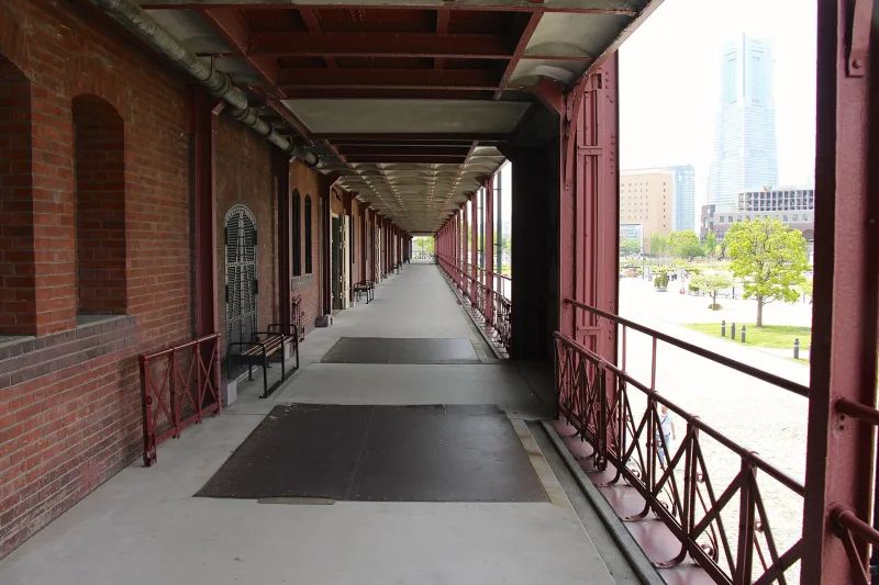 Brick-walled open corridor along the side of Building No. 2 with Minato Mirai towers beyond
