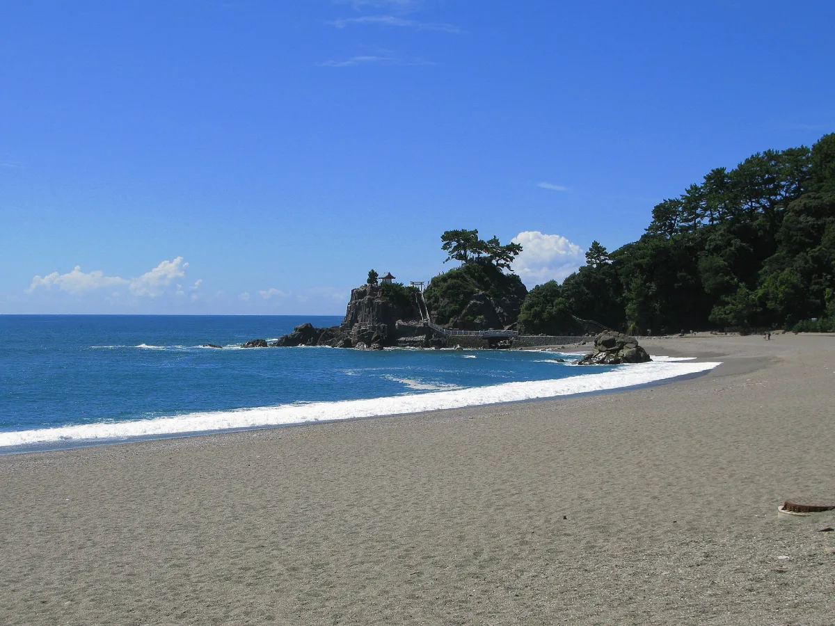The curved sandy beach of Katsurahama with blue Pacific waves and a pine-topped rocky cape