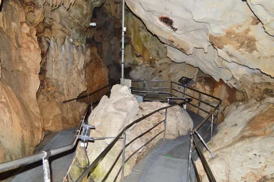 Handrailed walkway winding between cream-coloured limestone formations inside Ryugado Cave