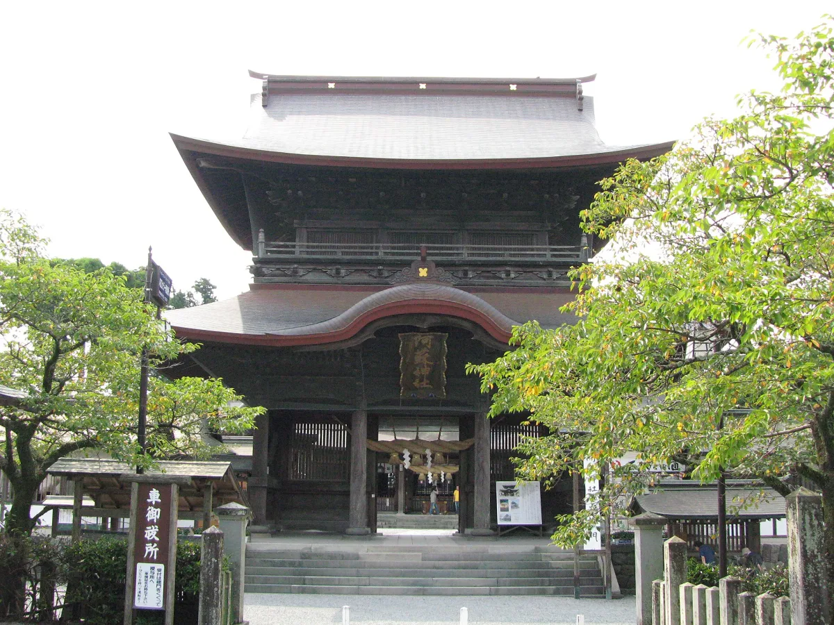 The two-storey Romon gate of Aso Shrine framed by green trees