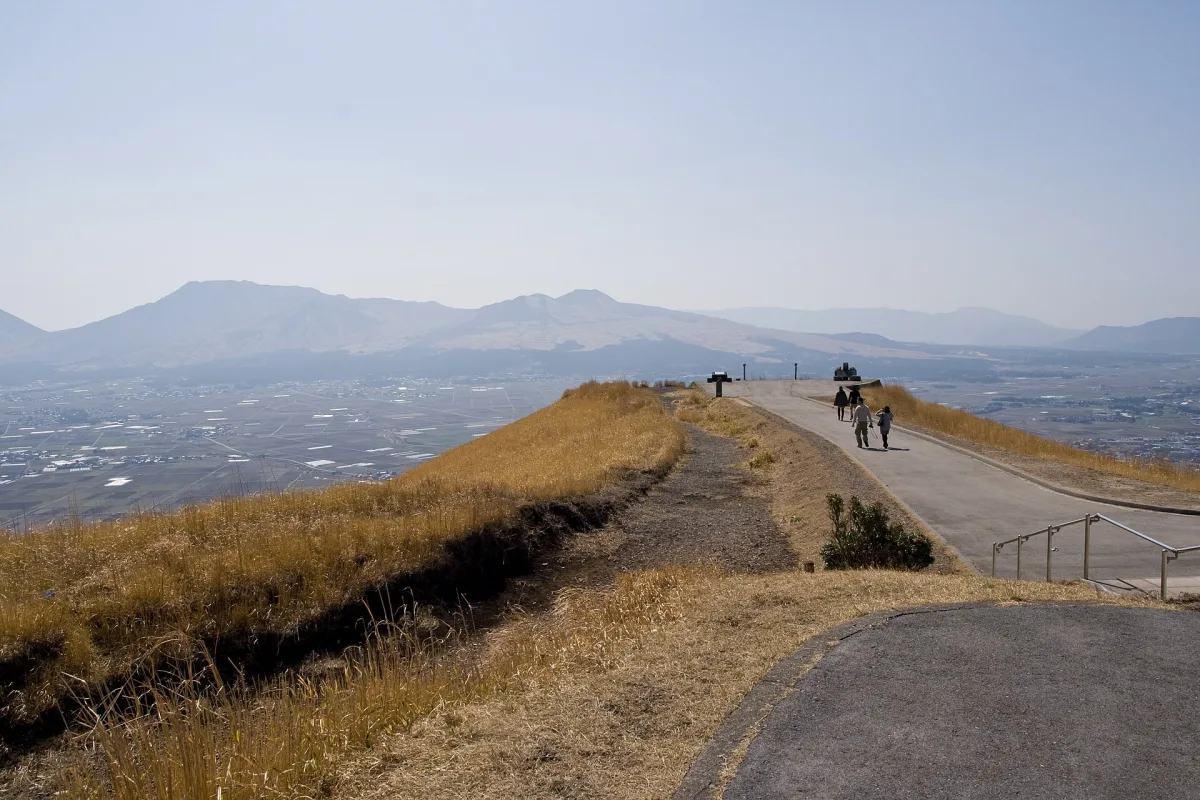 Walking path along the grassy ridge of Daikanbo with the Aso peaks in the distance
