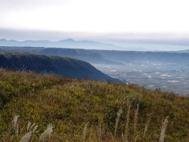 Grassy caldera rim and the wide Aso Valley below, seen from Daikanbo