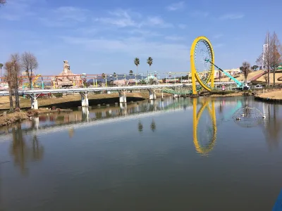 Pond and bridges at Greenland Amusement Park in Arao with a yellow loop coaster reflected in the water