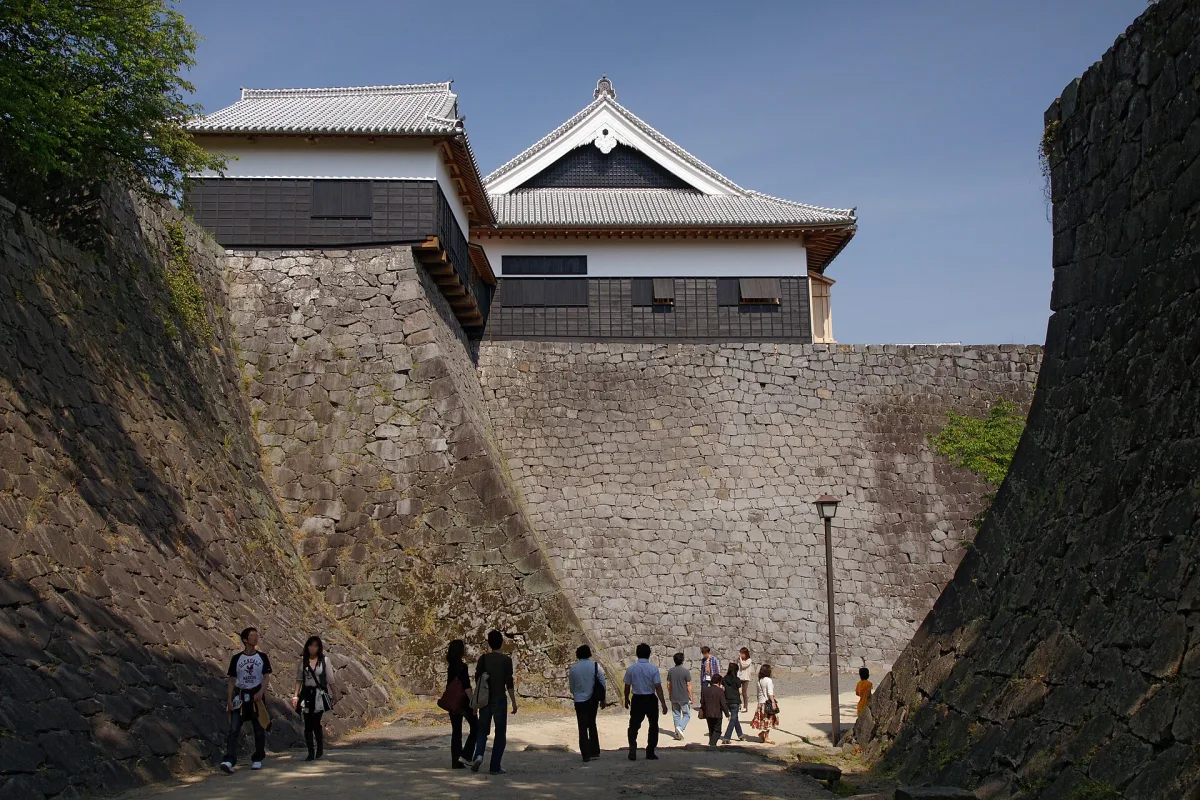 Black-and-white main keep and smaller keep of Kumamoto Castle on tall stone walls