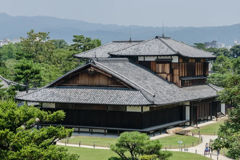 Honmaru Palace of Nijo Castle among pine trees, with mountains behind
