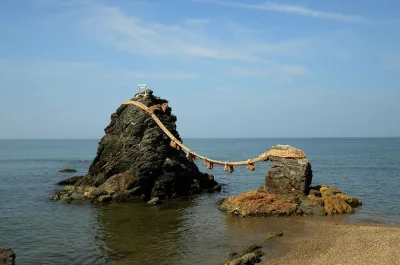 The two Meoto Iwa rocks joined by a thick straw rope in calm blue sea at Futami