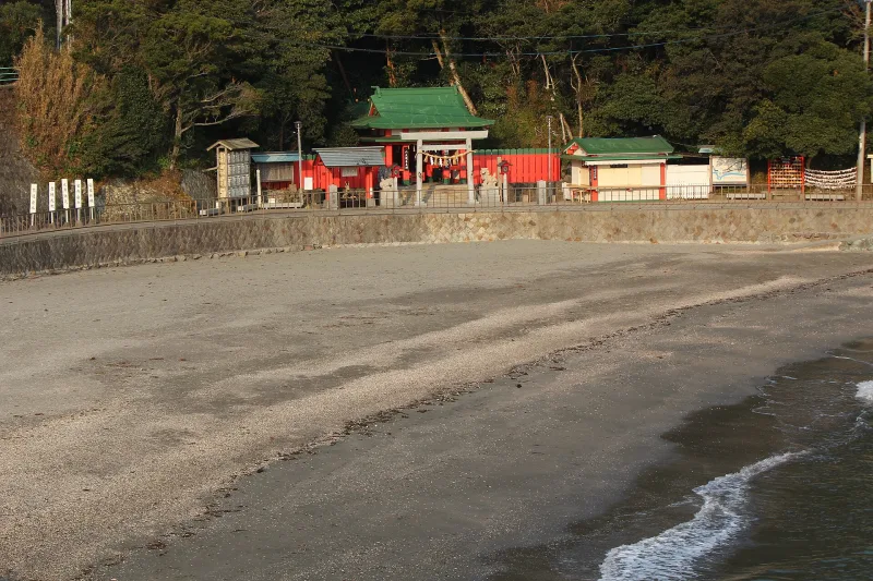 Small red and green Ryugusha shrine buildings along the sandy shore at Futami