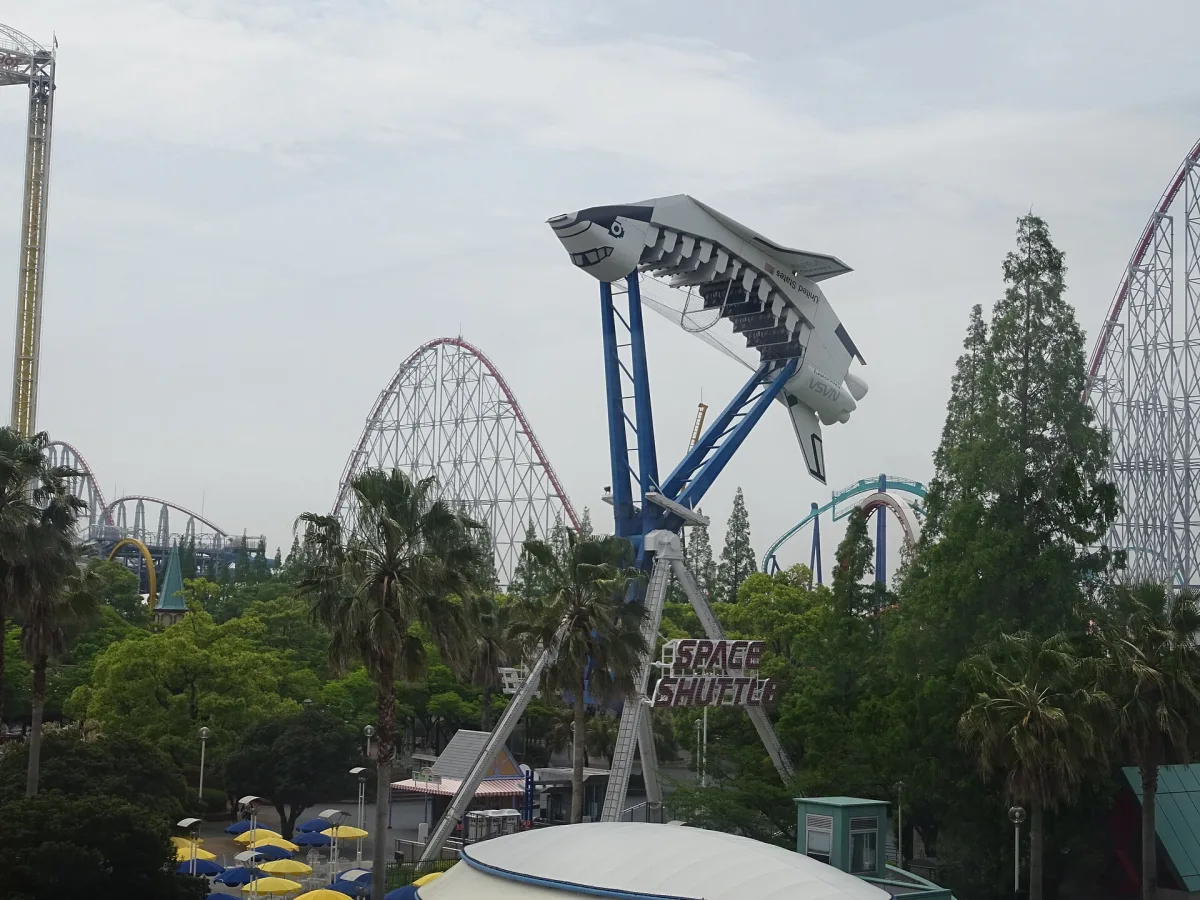 Shuttle-shaped ride in front of large roller coaster tracks at Nagashima Spa Land