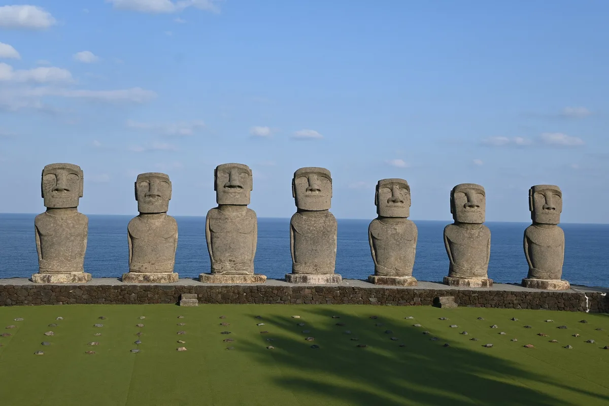 Seven moai statue replicas standing in a row against the blue Pacific at Sun Messe Nichinan