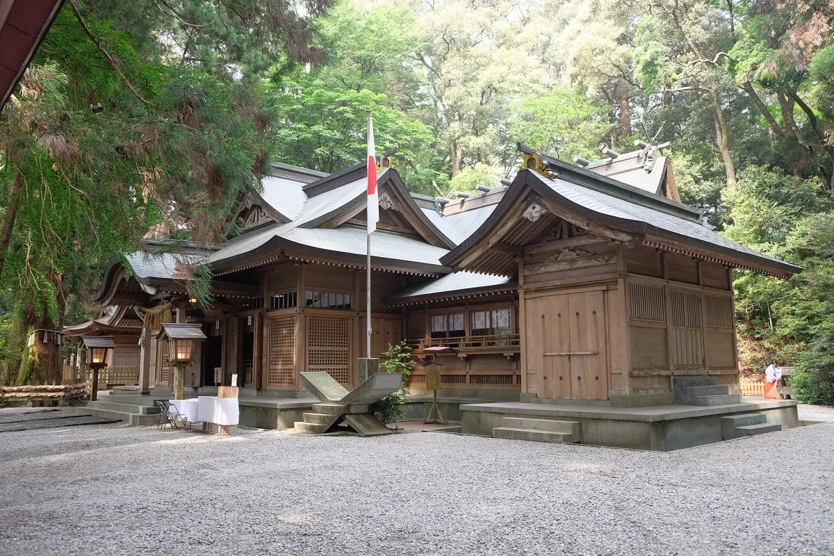Wooden worship hall of Takachiho Shrine surrounded by tall cedar trees