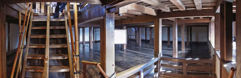 Steep wooden staircase and dark timber interior inside the Matsumoto Castle keep