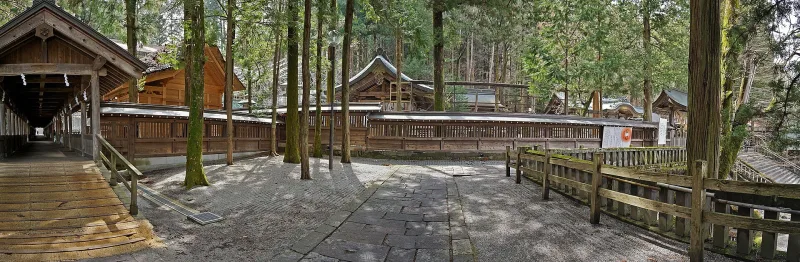 A roofed wooden corridor beside shrine buildings among tall trees at Suwa Taisha Kamisha Honmiya