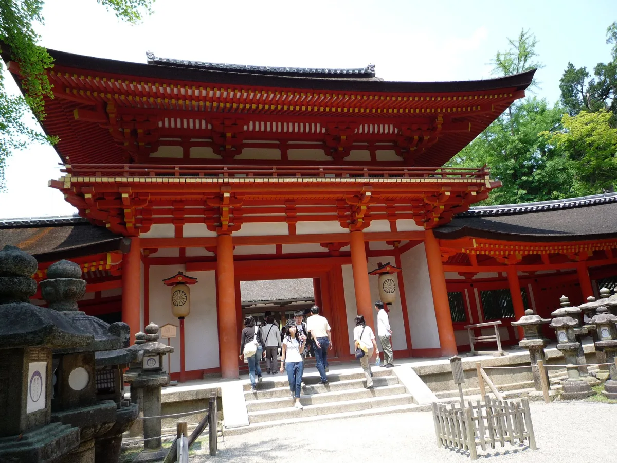 The vermilion two-storey Nanmon gate of Kasuga Taisha with stone lanterns in front