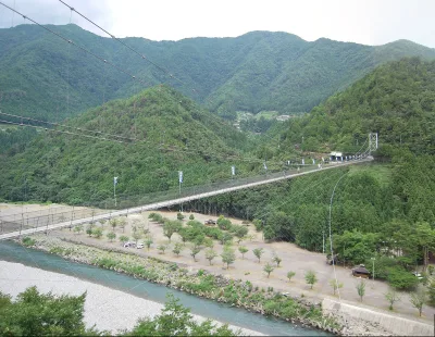 The long Tanize suspension bridge spanning a wide river valley between green mountains