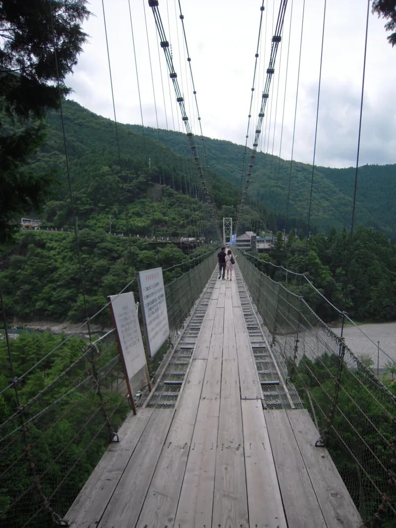 Wooden deck of the Tanize suspension bridge stretching ahead between wire railings
