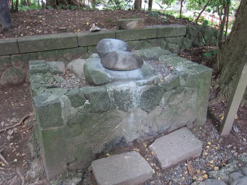 The Hinotama-ishi fortune stones on a stone pedestal in the grounds of Yahiko Shrine