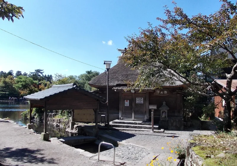 Thatched-roof communal bathhouse on the shore of Lake Kinrin