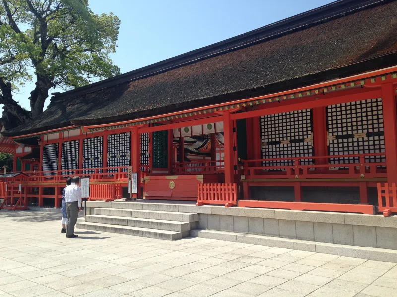 Vermilion worship hall of the first sanctuary at Usa Jingu with a large tree behind