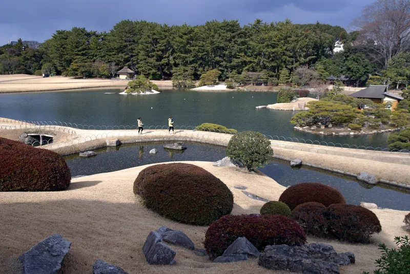 Wide pond, islands and clipped shrubs across the open landscape of Okayama Korakuen