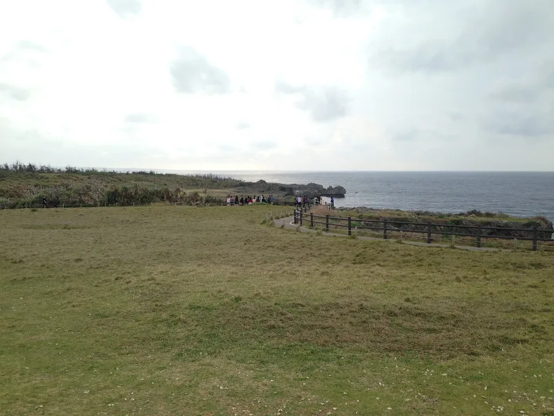 The flat grassy plateau on top of Cape Manzamo with a fenced walking path along the cliff edge