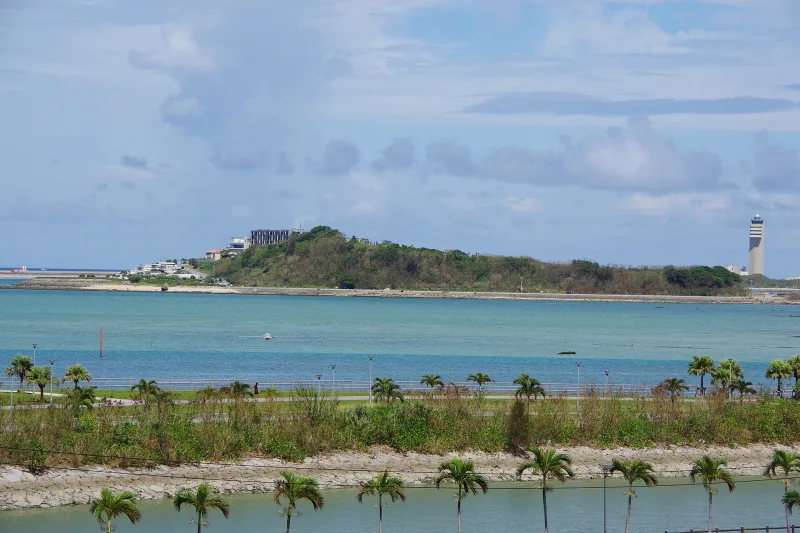 Senaga Island seen across turquoise water, with Naha Airport's control tower on the right