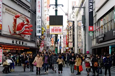 Crowded Dotonbori street lined with giant signs, including a huge mechanical crab