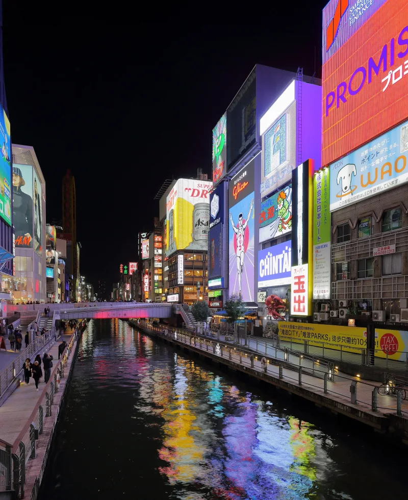 Neon signboards reflected in the Dotonbori canal at night near Ebisu Bridge