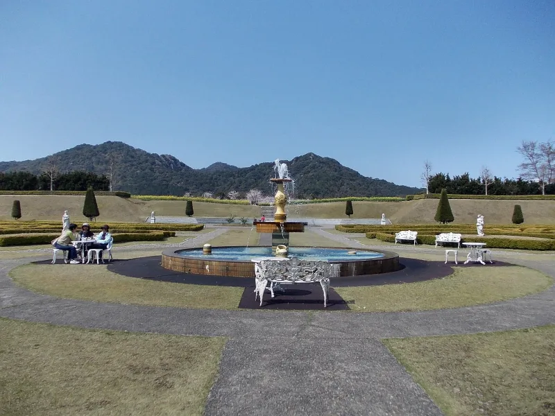 Fountain in the formal baroque garden of Arita Porcelain Park with hills behind