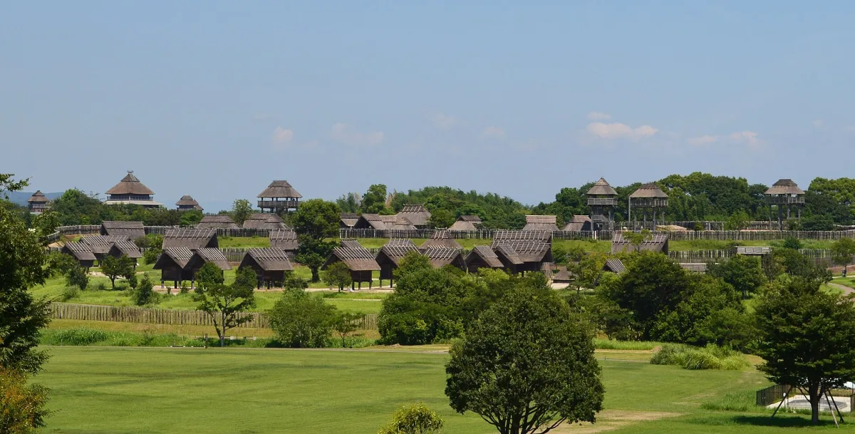 Wide view of the reconstructed Yayoi-period moated village with thatched buildings and watchtowers