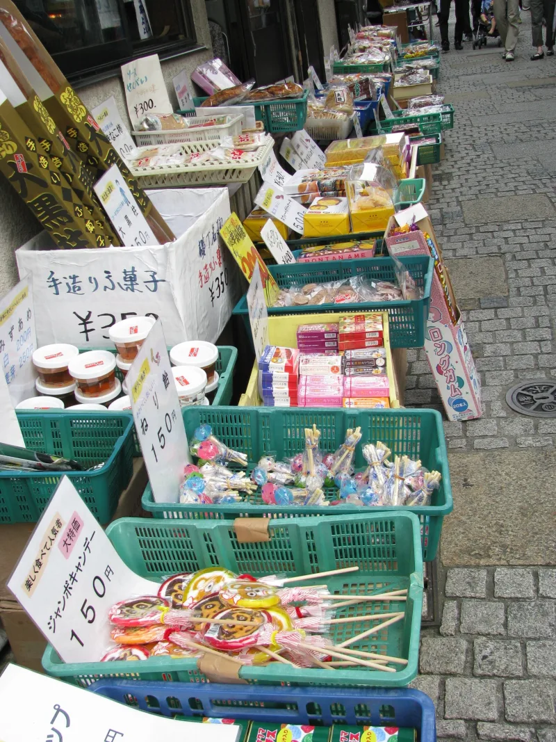 Colorful dagashi candies displayed in trays outside a shop in Kashiya Yokocho