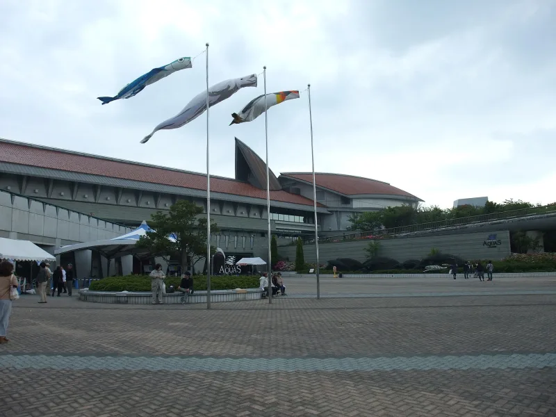 The exterior and entrance plaza of the Shimane Aquarium AQUAS building with carp streamers on poles