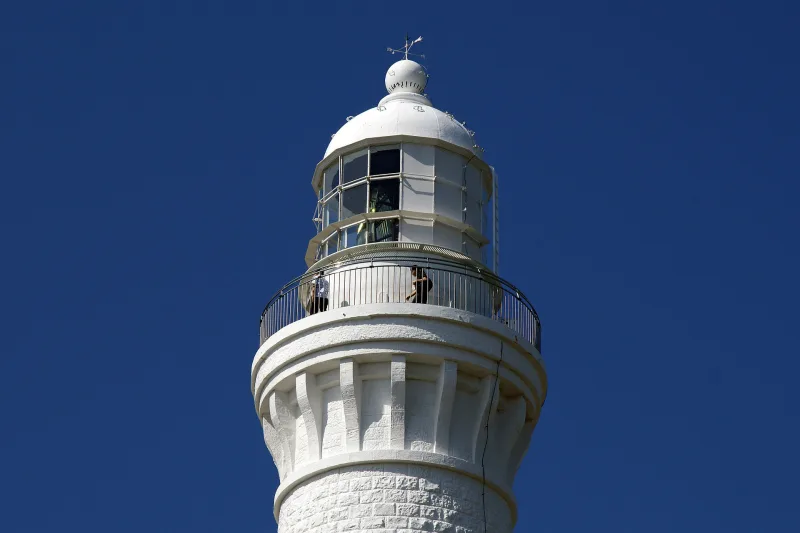 The lantern room and viewing balcony at the top of Hinomisaki Lighthouse against a deep blue sky