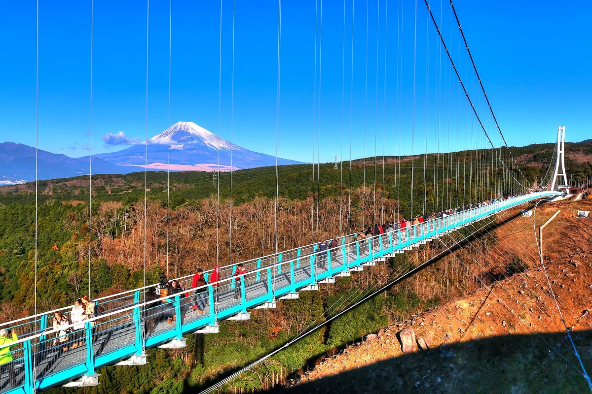 The long Mishima Skywalk suspension bridge with snow-capped Mount Fuji behind