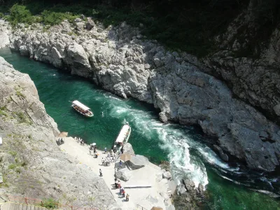 Sightseeing boats on the green Yoshino River between white rock walls of Oboke Gorge