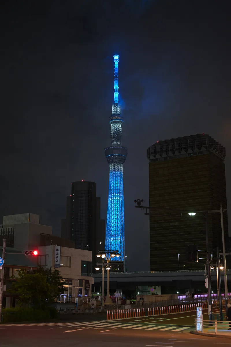 Tokyo Skytree lit in light blue at night, seen from Asakusa