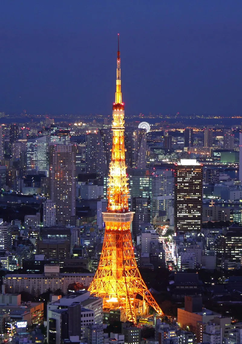 Tokyo Tower glowing orange at night above the lights of central Tokyo