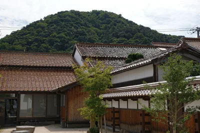 Red-tiled roofs and white-walled storehouses of Kurayoshi with forested Mt. Utsubuki behind