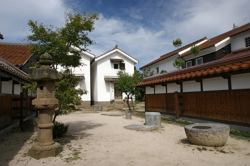 White storehouses with dark wooden lower walls and red roof tiles around a courtyard in Kurayoshi