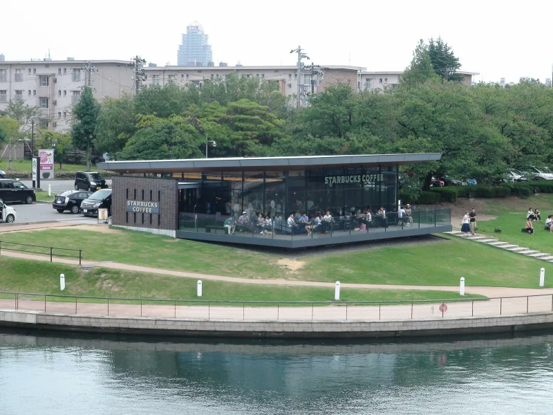 Glass-walled Starbucks cafe on the lawn beside the canal in Kansui Park, Toyama