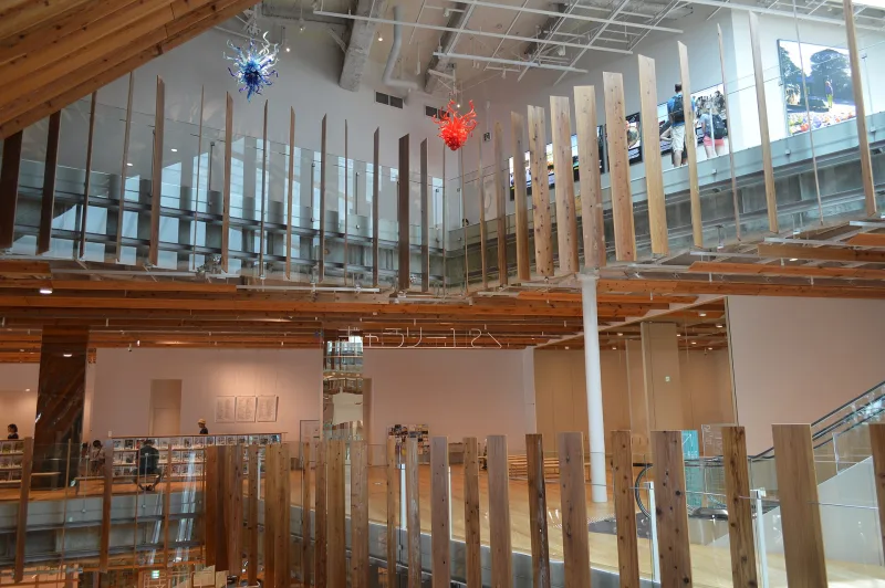 Inside the Toyama Glass Art Museum with glass artworks hanging above wooden balustrades