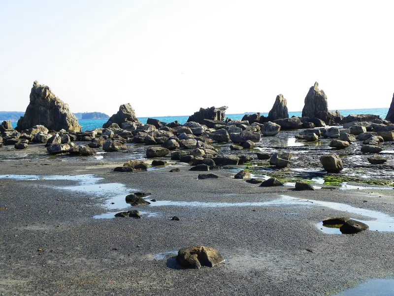 Rock pillars of Hashigui-iwa with boulders scattered on the exposed seabed at low tide