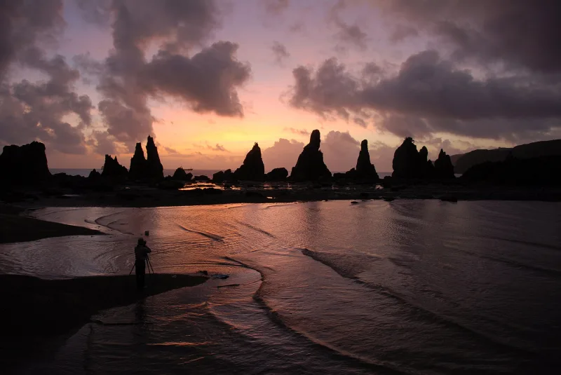 Silhouettes of the Hashigui-iwa rocks against a pink dawn sky