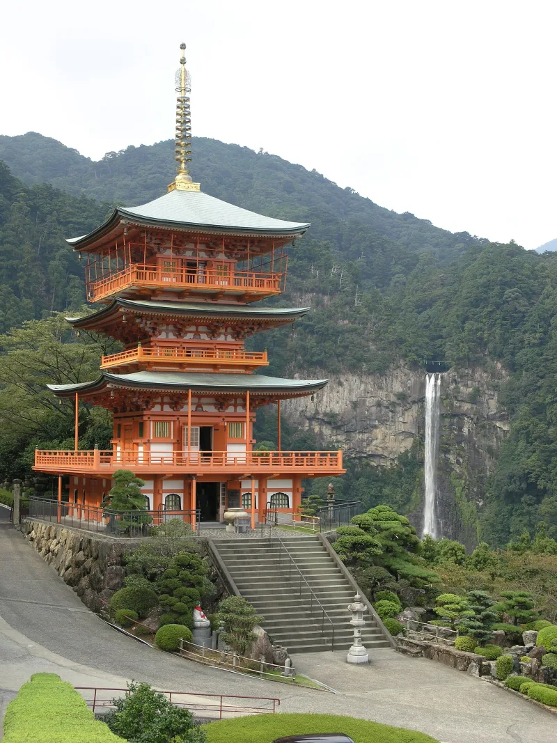The vermilion three-storey pagoda of Seigantoji with Nachi Falls on the mountainside behind