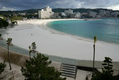 The curving white sand of Shirarahama Beach beside turquoise water, with hotels on the hills behind